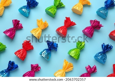 Candies in colorful wrappers on light blue background, flat lay Royalty-Free Stock Photo #2063702357