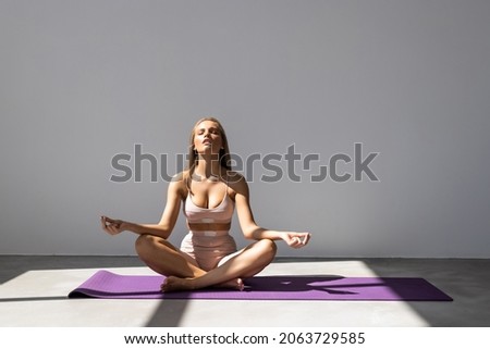 young woman practicing yoga in the lotus position, isolated on white