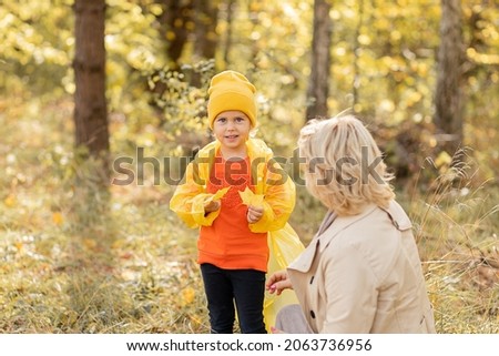 Photo of young woman mom is walking in autumn park with daughter little girl, playing and have together fun with autumn yellow leaves
