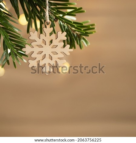 Zero waste and eco friendly christmas concept. Wooden snowflake on a Christmas tree branch on background of wooden wall. Horizontal banner, copy space