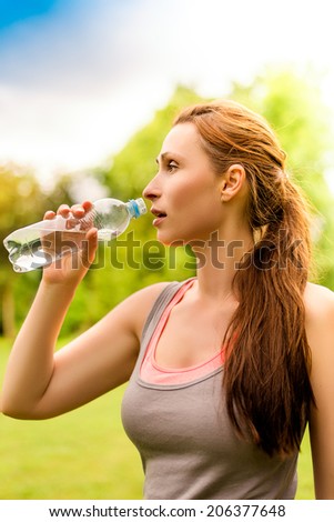running jogging female in park drinking water bottle