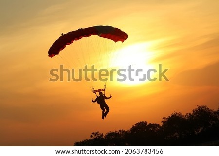 Skydiver landing the parachute at the sunset Royalty-Free Stock Photo #2063783456