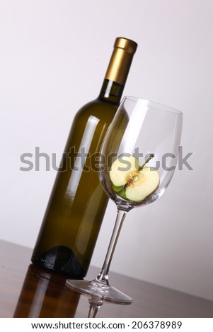 Bottle of white wine and a glass with apple over a white background