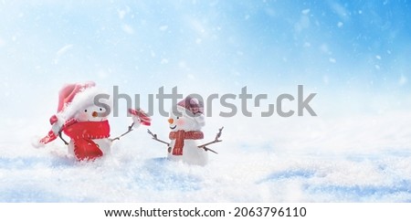 Snowman giving friend christmas gift box in snowy landscape