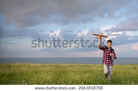Boy launching an airplane into the sky in autumn at sunset. A teenager dreams of flying an aviator. Evening walk for children in the field. Active recreation concept in nature. Place for text