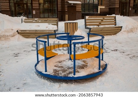 Children's playground with a carousel in the winter courtyard.
