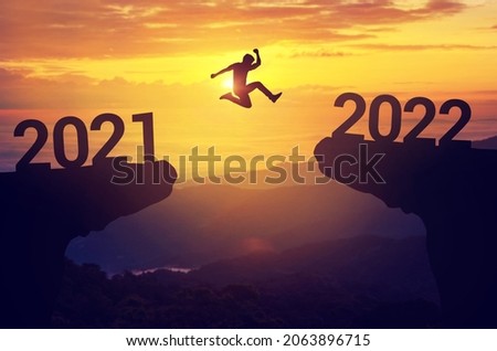 Silhouette man jump between 2021 and 2022 years with sunset background, Success new year concept. Royalty-Free Stock Photo #2063896715