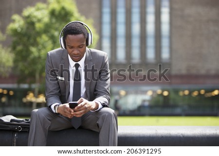 Portrait of African American Businessman listening to music with headphones outdoors Royalty-Free Stock Photo #206391295