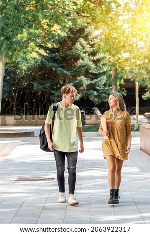 Two young university students, a man and a woman, walking around campus and talking about their studies Royalty-Free Stock Photo #2063922317