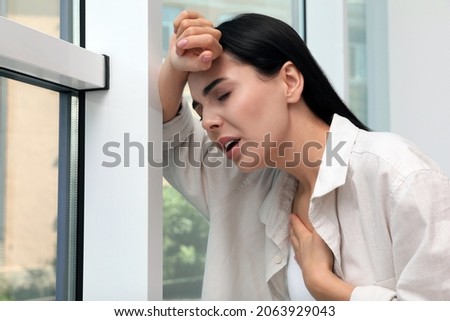 Young woman suffering from breathing problem near window indoors Royalty-Free Stock Photo #2063929043