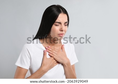 Young woman suffering from breathing problem on light background Royalty-Free Stock Photo #2063929049