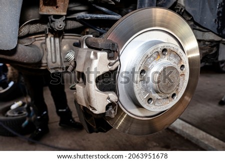 New rear brake calipers and brake discs with pads in a passenger car, on a car jack in the workshop. Royalty-Free Stock Photo #2063951678