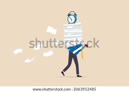 Busy workload and deadline causing exhaustion and burnout, overload or overworked office routine concept, tired businessman carrying heavy documents paperwork with alarm clock deadline on top. Royalty-Free Stock Photo #2063952485