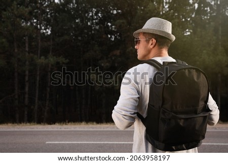Man with backpack on road near forest