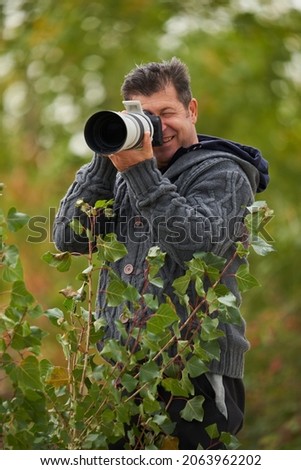 Professional wildlife photographer outdoor in the bush, shooting with a telephoto lens