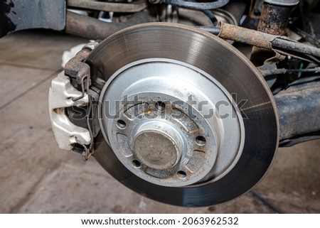 New rear brake calipers and brake discs with pads in a passenger car, on a car jack in the workshop. Royalty-Free Stock Photo #2063962532