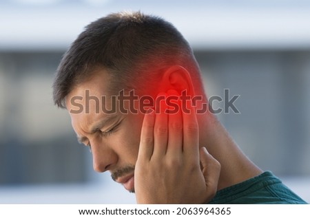 Man suffering from strong earache or ear pain. Ear inflammation, otitis or tinnitus Royalty-Free Stock Photo #2063964365