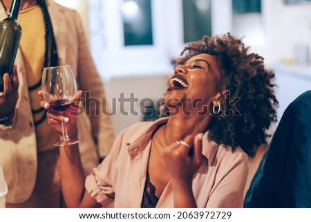 smiling happy african lady at table - african american woman laughing at party - young female person holding glass of wine at dinner 