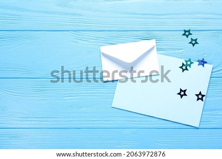 Blank card with envelope and stars on blue wooden background