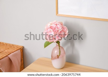 Vase with hydrangea flowers on table near color wall