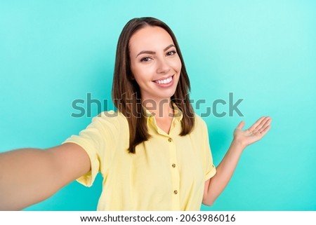 Photo of lovely young brunette lady do selfie index empty space wear yellow top isolated on teal color background