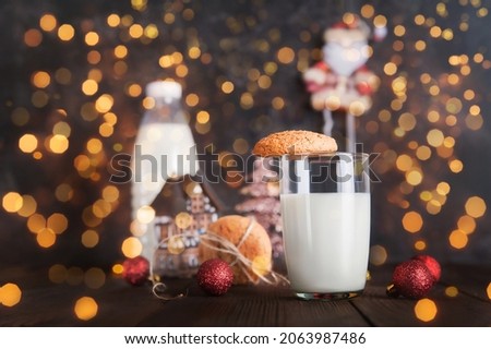 Glass of milk for Santa Claus and Christmas cookies on dark background close-up and copy space concept.