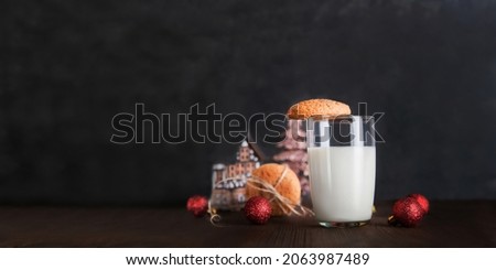 Glass of milk for Santa Claus and Christmas cookies on dark background close-up and copy space concept.