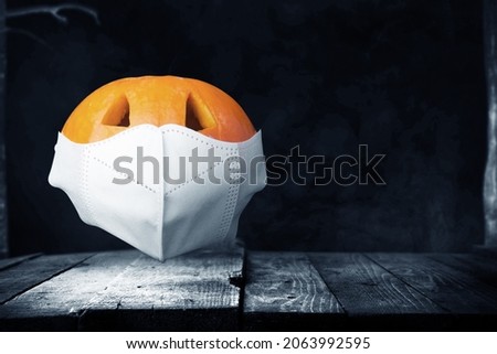 Jack-o-Lantern in the face mask on a wooden table with dark background