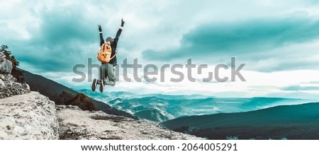 Man traveler on mountain summit enjoying nature view with hands raised over clouds - Sport, travel business and success, leadership and achievement concept Royalty-Free Stock Photo #2064005291