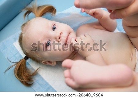a little nursing girl lies on her back on a massage on a changing table
