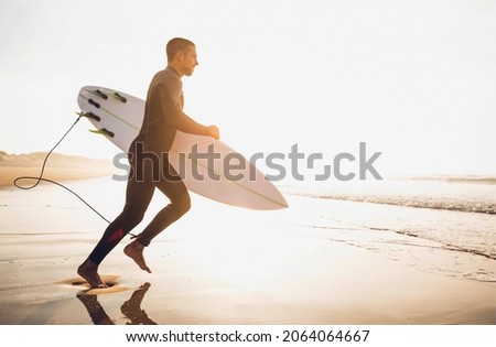 A surfer with his surfboard running to the waves Royalty-Free Stock Photo #2064064667