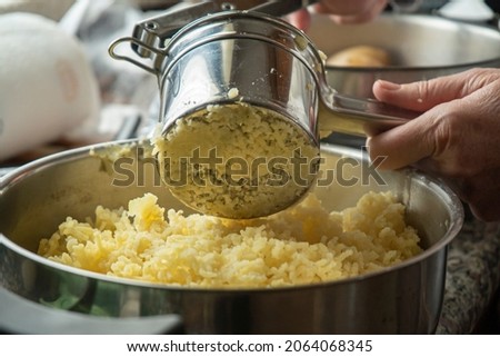 The process of making puree with stainless steel potato masher, close up. Step-by-step recipe for preparing delicious vegetable or vegetarian dishes for cooking blog. Royalty-Free Stock Photo #2064068345