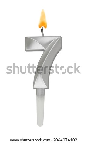 Burning silver birthday candle isolated on white background, number 7