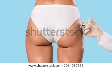Non-Sugical Butt Lifting Sculptra Concept. Rear back view of young lady getting hip injection at beauty salon, closeup cropped. Surgeon making injection at buttocks area, isolated on studio background Royalty-Free Stock Photo #2064087338