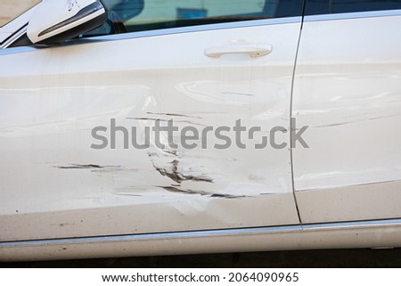 Close up picture of damage on white car door after minor accident