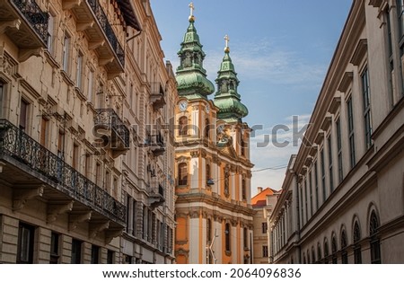 Ancient towers of University Church among historical buildings in the old town of Budapest, Hungary, Europe. Facade of a Catholic church in the V. district, the true inner city of Pest. Royalty-Free Stock Photo #2064096836