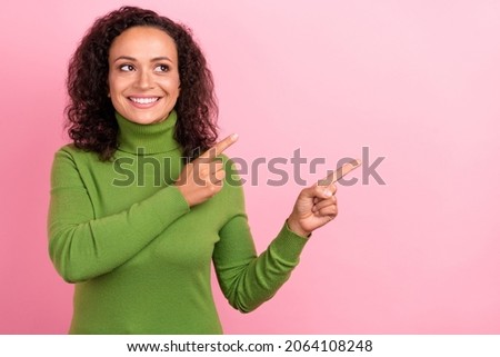 Photo of funny charming african lady dressed green turtleneck smiling looking pointing empty space isolated pink color background