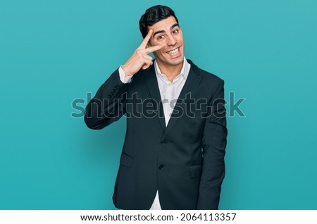 Handsome hispanic man wearing business clothes doing peace symbol with fingers over face, smiling cheerful showing victory 