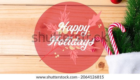 Composition of happy holidays text over christmas decorations on table. christmas, winter, tradition and celebration concept digitally generated image.