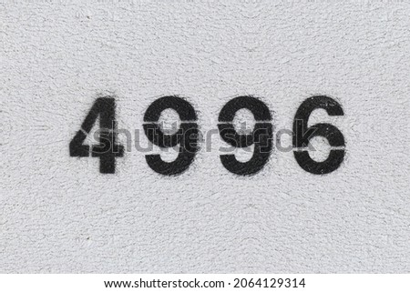 Black Number 4996 on the white wall. Spray paint. Number four thousand nine hundred ninety six.
