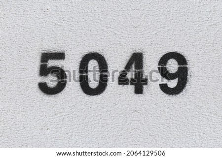 Black Number 5049 on the white wall. Spray paint. Number five thousand forty nine.