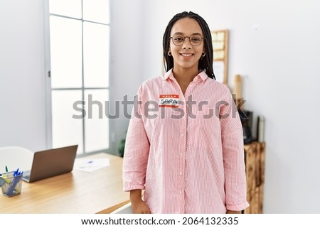 Young african american woman wearing hello my name is sticker identification looking positive and happy standing and smiling with a confident smile showing teeth 