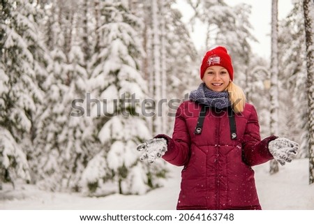 teenage girl in a red jacket throwing snow and laughing in a snowy forest