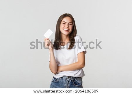 Attractive happy brunette girl laughing and holding credit card, white background