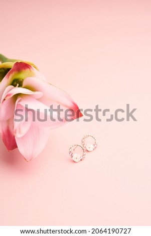 Jewelry fashion photography. Earrings on a pink flower on pinl background. content creative minimalist shooting.