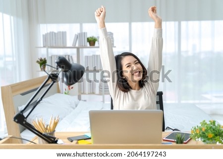 A photo of a bright Asian woman working at home, in the bedroom. The idea is: Workform Home, Finance, Marketing, Bright, Portrait, Simple.