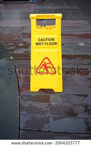 Yellow Warning Sign of slippery wet floor against the background of the wet floor beside the pool