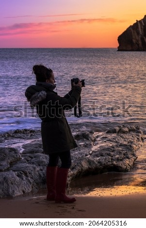 girl taking pictures in the sea, when it dawns in the north of Spain, to the mountains and skies full of colors
