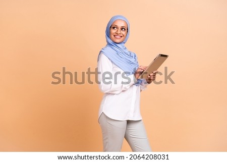 Profile photo of young arabic modern lady look promo write tablet wear headscarf shirt eyewear pants isolated on beige background