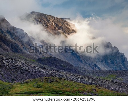 Soft focus. White cloud descended on the dark mountain peaks. Light in the morning mountains. Bright autumn natural high-mountain background.